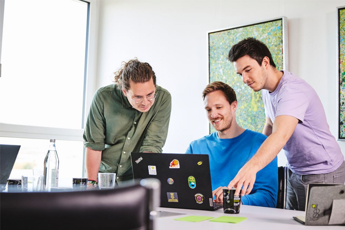 Drei lise-Entwickler beraten sich gegenseitig vor einem Computer über den passenden Managed-Cloud-Service-Anbieter