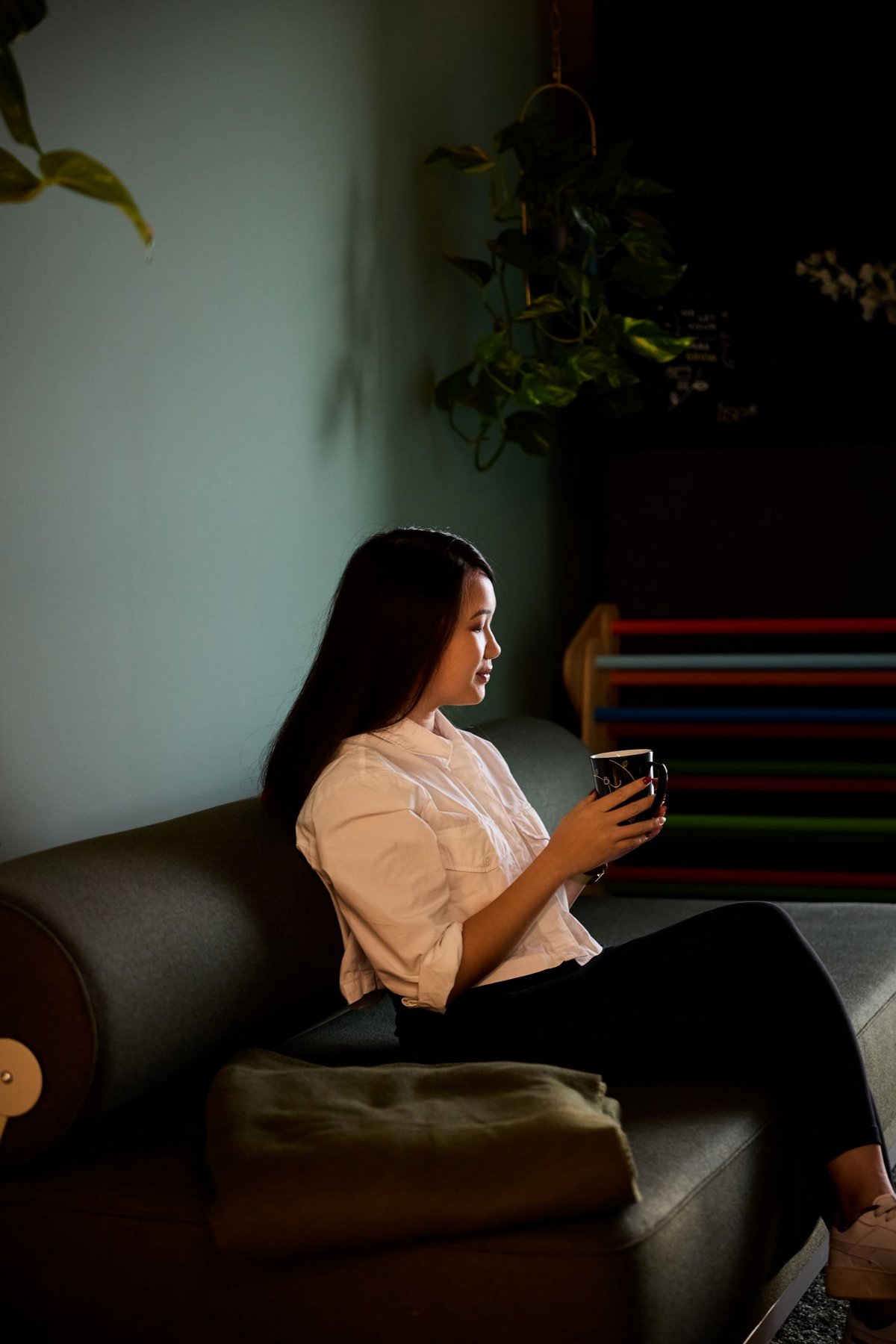 Eine lise-Entwicklerin macht Pause in einem grünen abgedunkelten Raum auf einem schwarzen Sofa