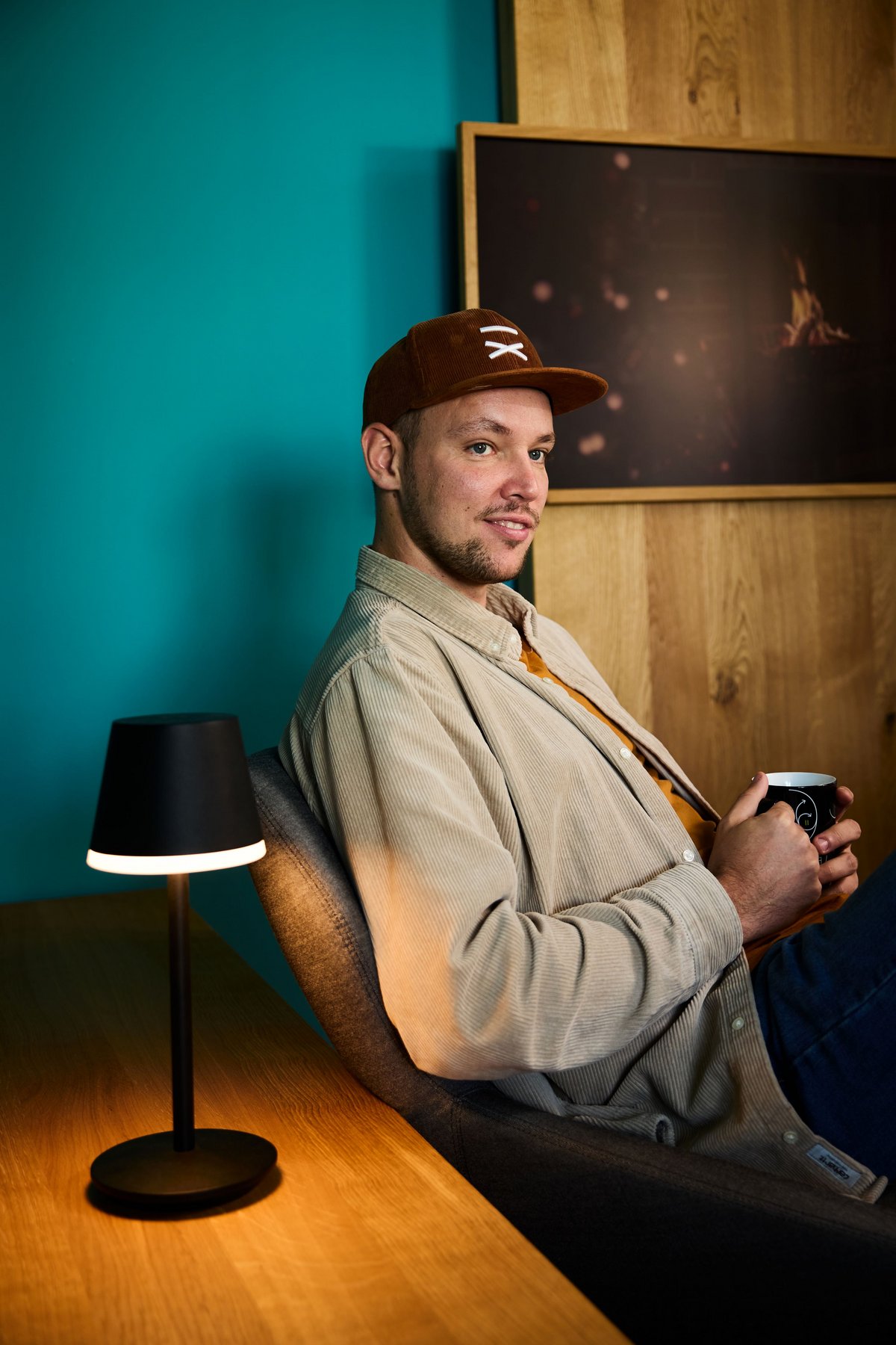 Ein lise-Entwickler macht gerade Pause auf einem Sessel mit einer kleinen Lichtquelle und vor einer türkisenen Wand