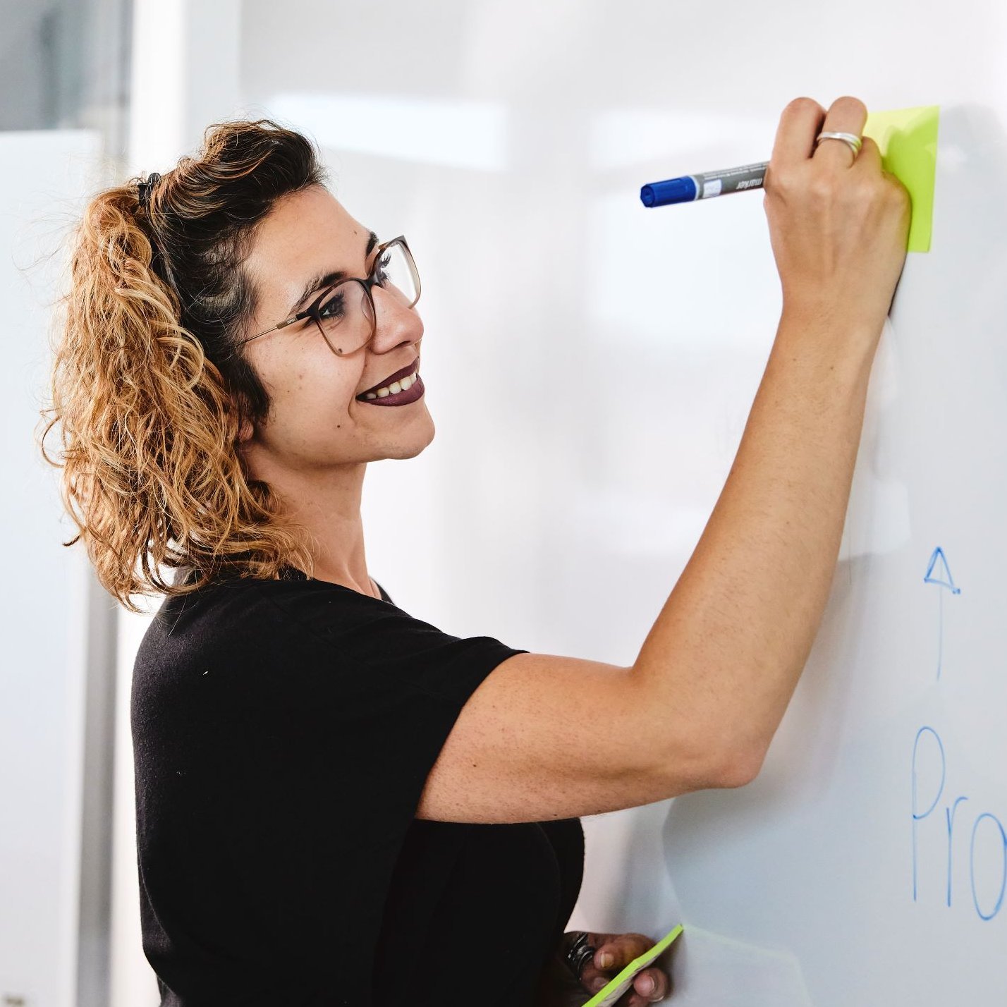 Eine lise-Entwicklerin bringt Ideen zur Produktstrategie auf einem Whiteboard zusammen