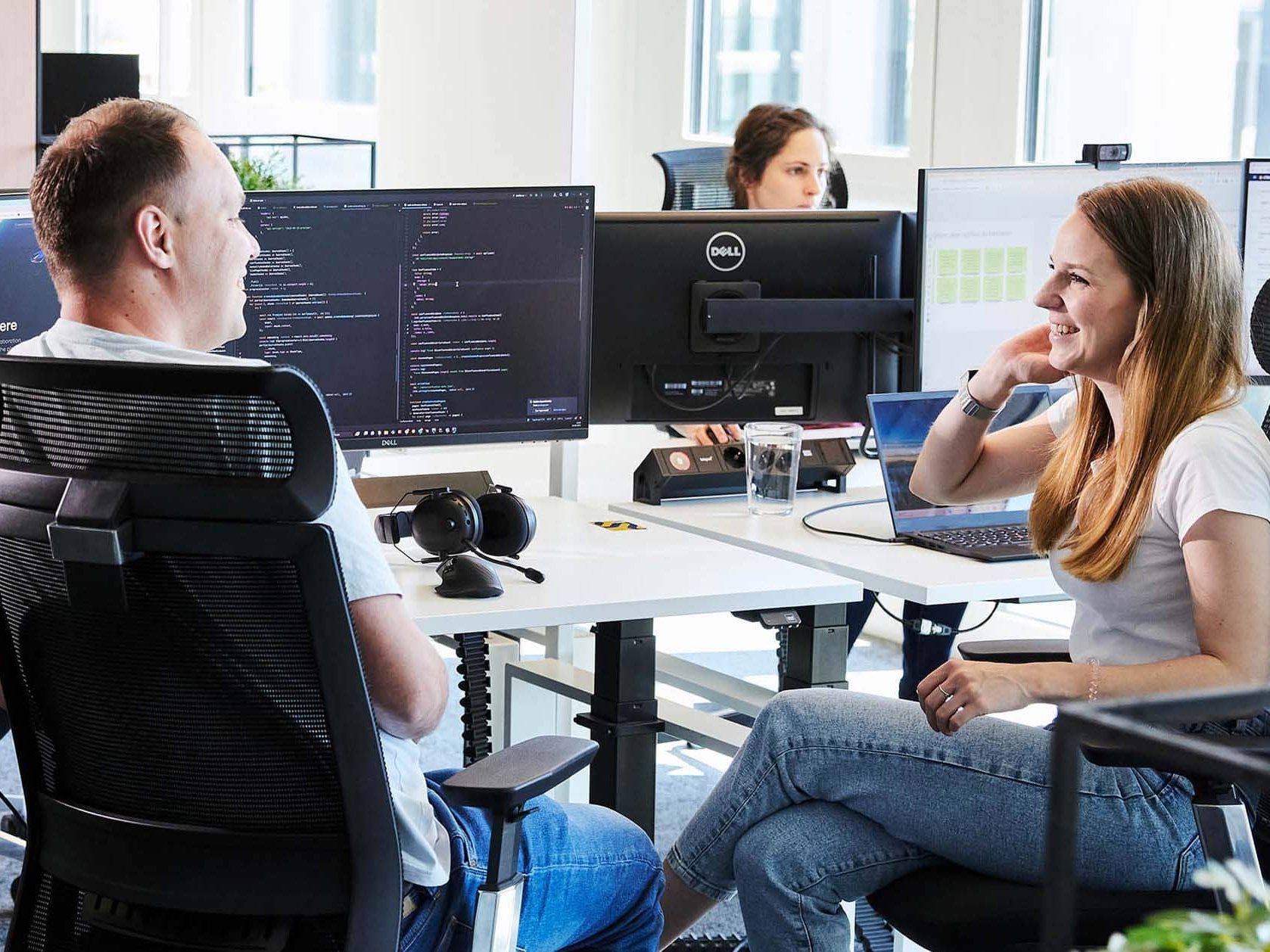 Zwei lise-Mitarbeiter*innen besprechen sich im Vordergrund vor einem Computer über einen neuen M365 Consultant