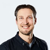 Foto eines grinsenden lise-Product Owners in einem schwarzen Hemd mit zurückgekämmten Haaren