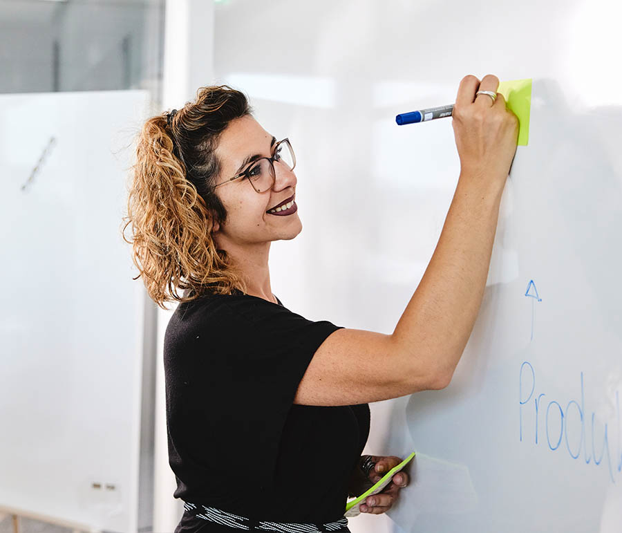 Eine lise-Entwicklerin notiert die erarbeitete UX-Strategie auf einem Whiteboard