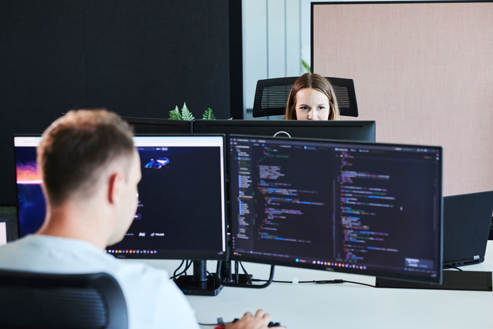 Ein lise-Mitarbeiter ist von hinten zu sehen, wie er mit Codes auf einem Computer Software-Lösungen entwickelt