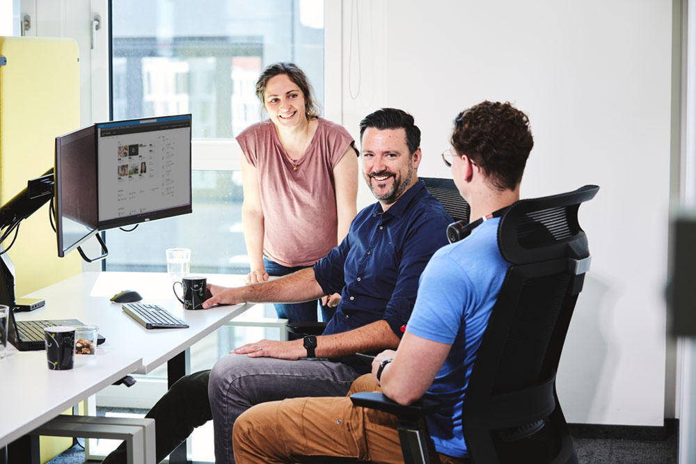 Drei lise-Mitarbeiter tauschen sich mit Hilfe von SharePoint auf dem Computer über den neusten Stand aus